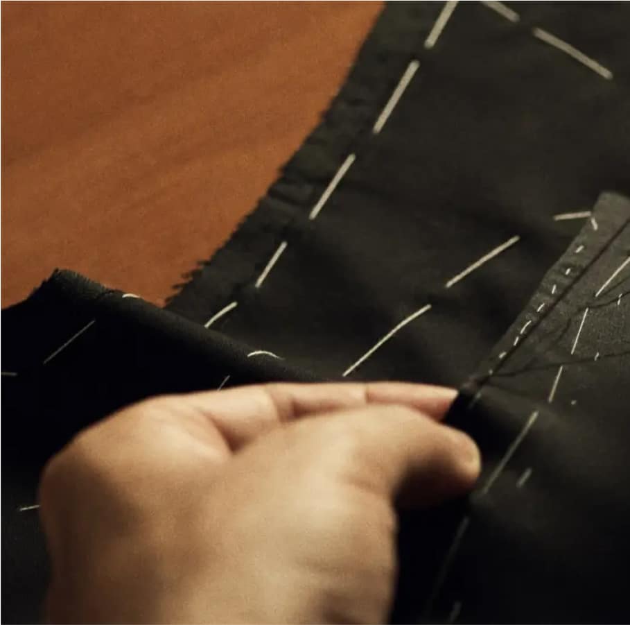 Artisan hand-sewing detailed stitching on a bespoke jacket